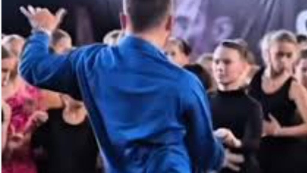 A promotional image for the 'blue shirt guy dance song,' featuring a close-up of a man in a blue shirt mid-dance with a playful, retro aesthetic.